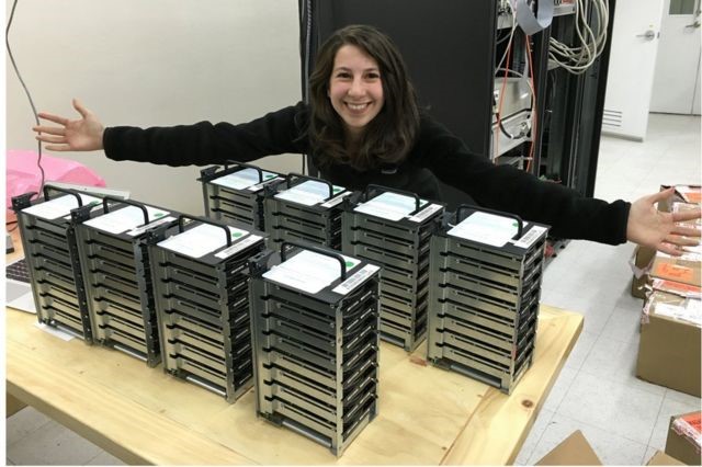 Figura 2. Katherine Bouman y los discos duros que contienen la información para el procesamiento de la primera imagen del agujero negro. Tomada de https://www.bbc.com/mundo/noticias-47880446